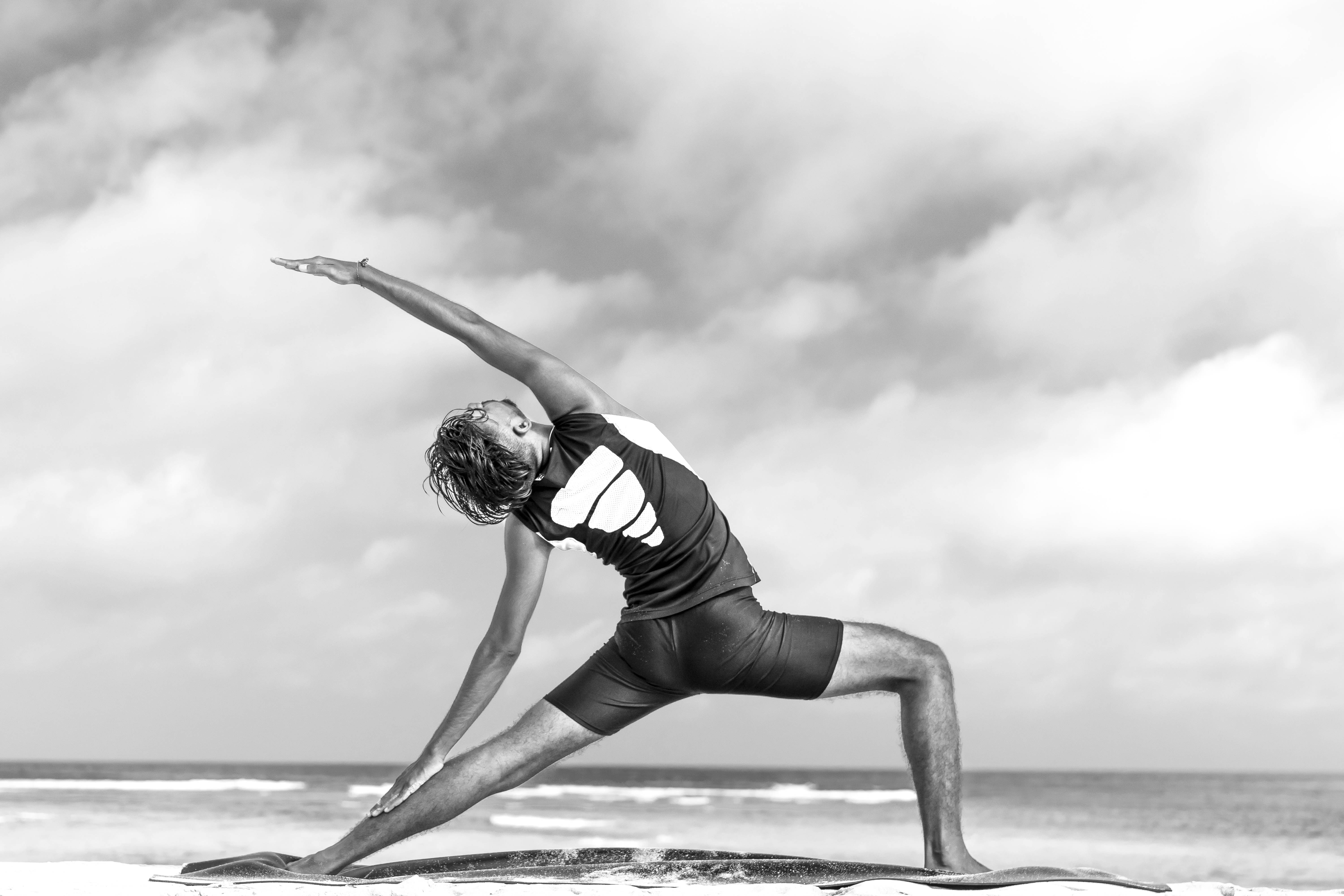 Yogi am Strand von Bali, hinter ihm das blaue Meer, junger Mann übt Yoga
