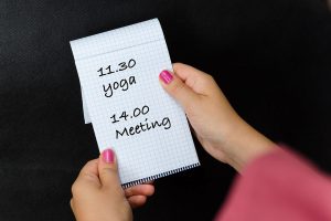 Junge Frau hält Notizblock mit Yogatermin
