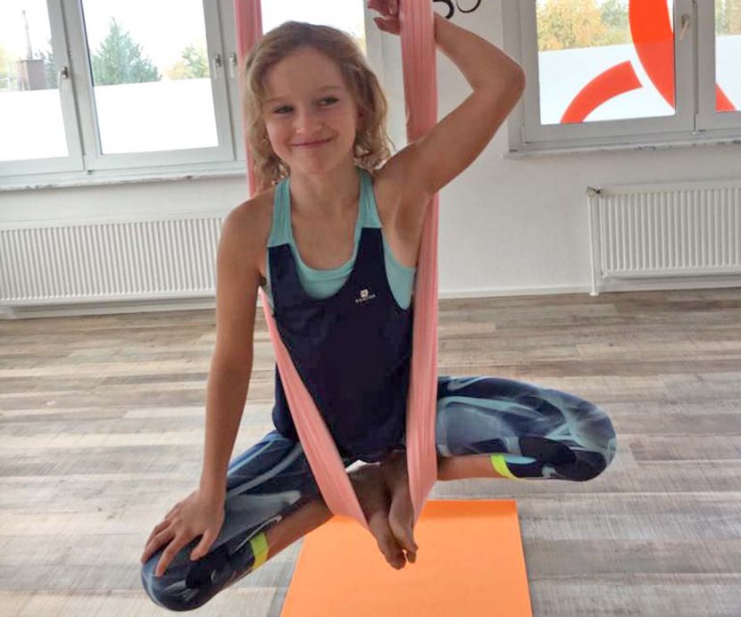 Aerial Yoga, Kinderkurse, Mädchen hängend in der Luft im Aerial Yoga Tuch, lacht