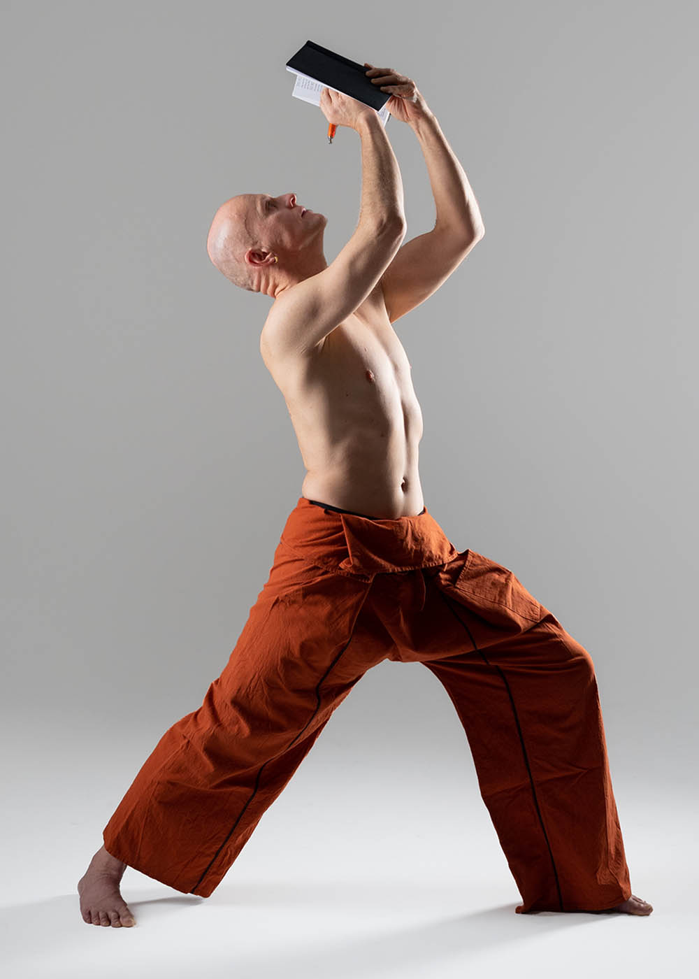 Christian Bechtel in Yoga-Haltung Krieger schreibt gleichzeitig in Notizbuch