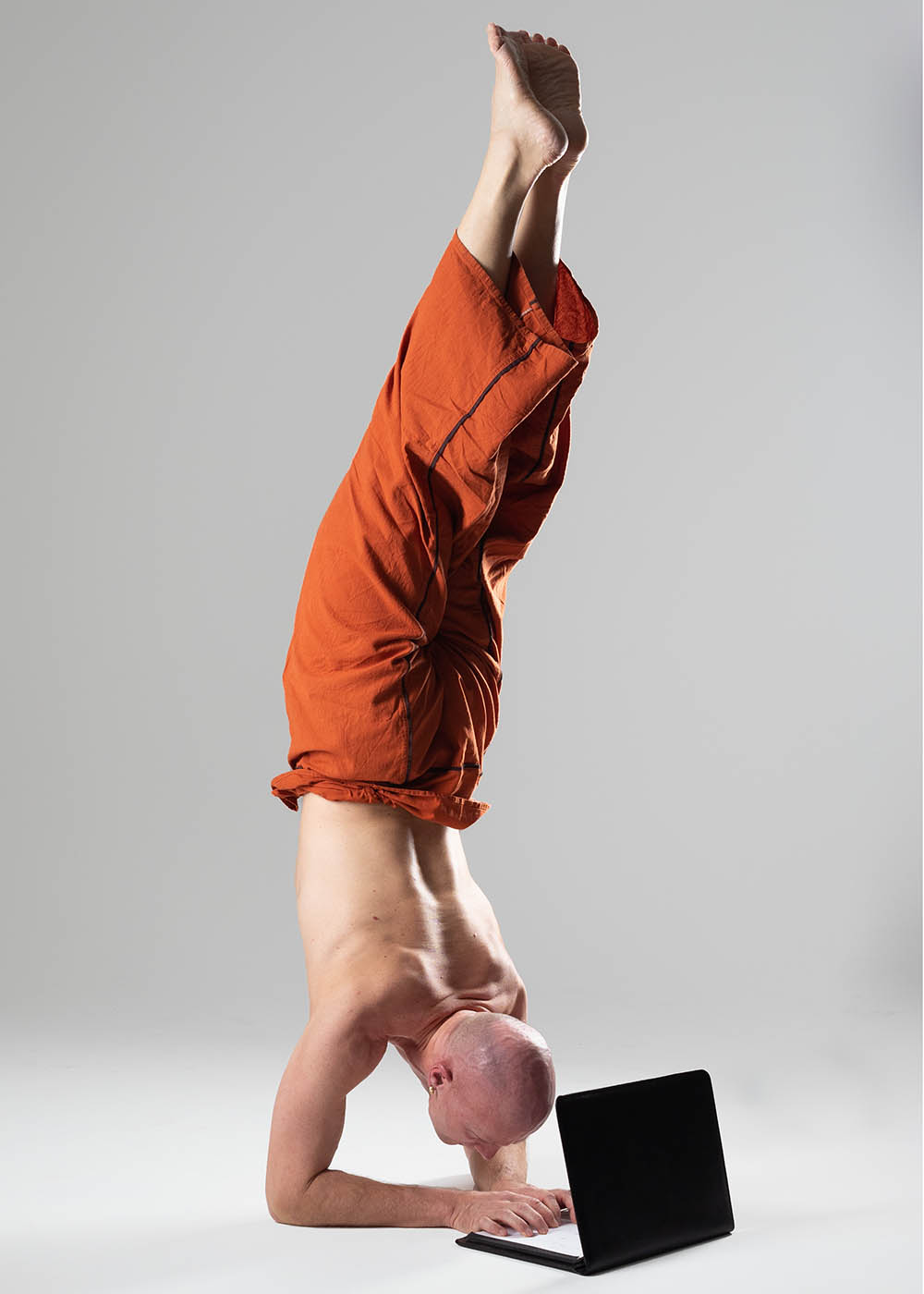 Christian Bechtel macht Handstand und tippt gleichtzeitig auf Laptop